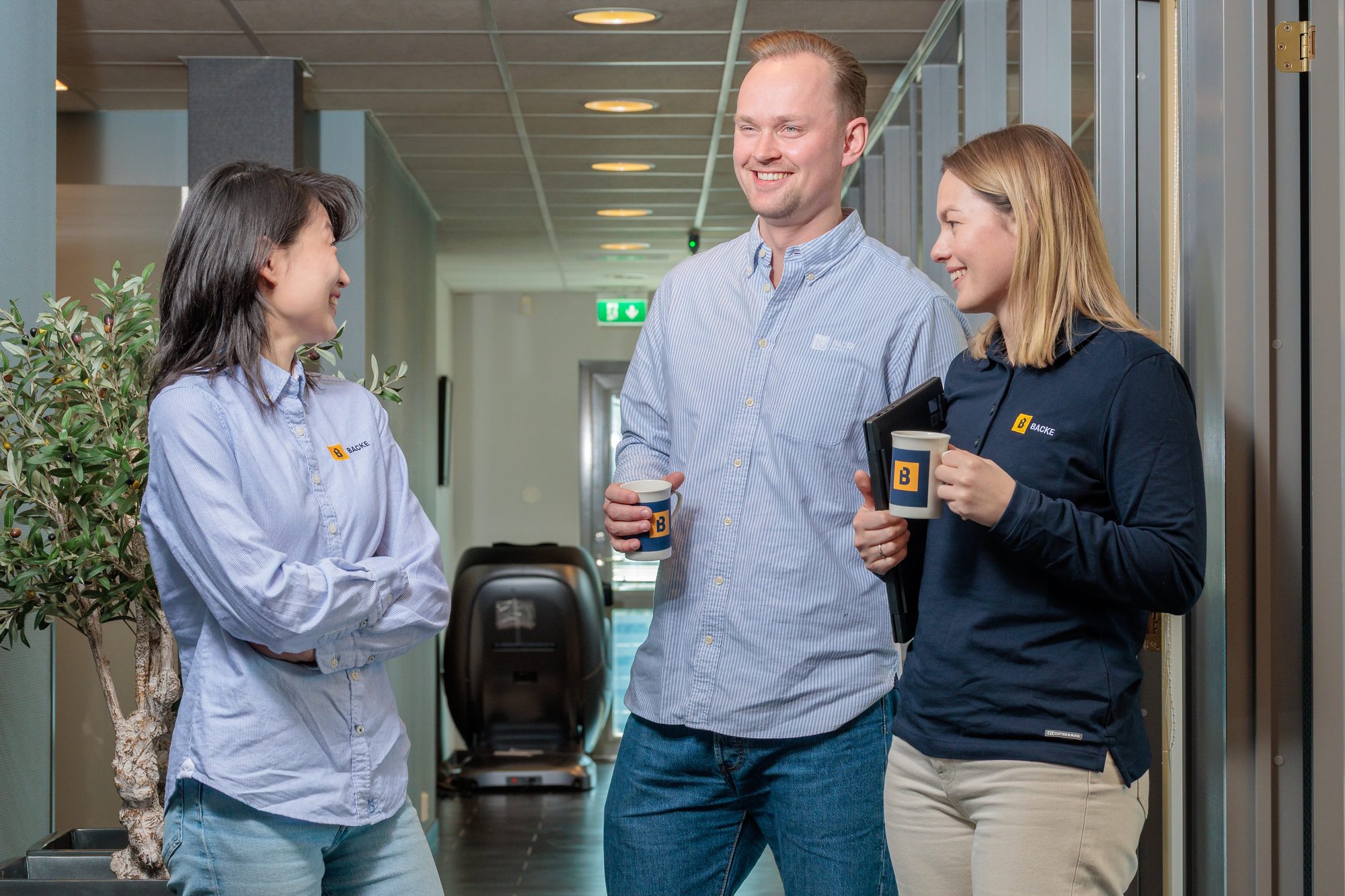Ansatte hos Backe ved logoen på kontoret i Fredrikstad