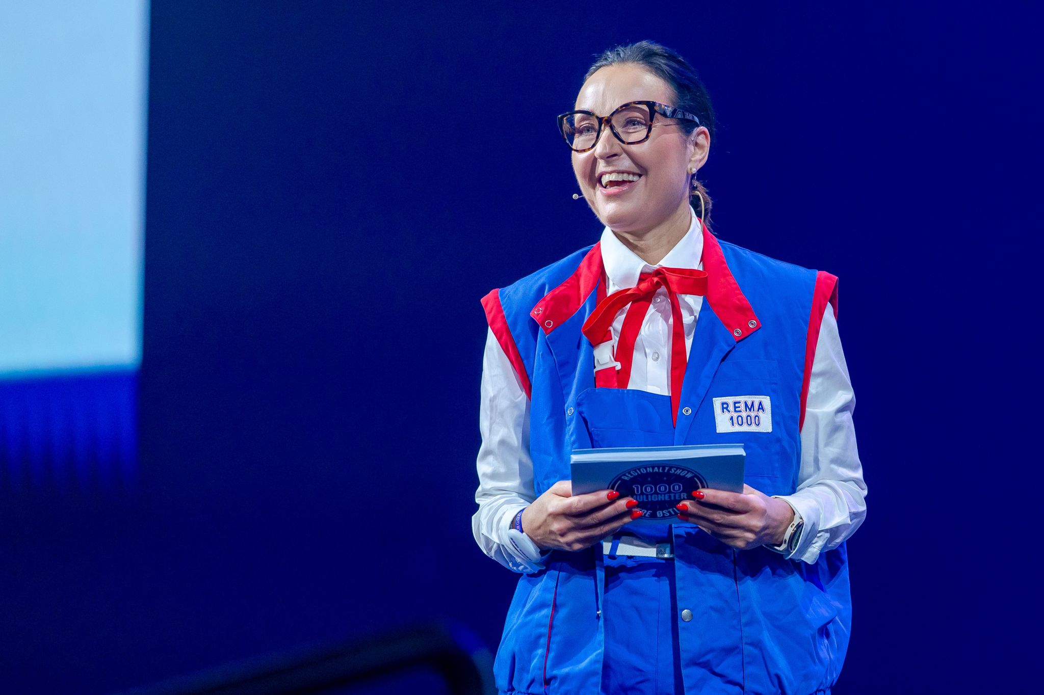 Programleder i Rema 1000-uniform på scenen under regionshow i Moss